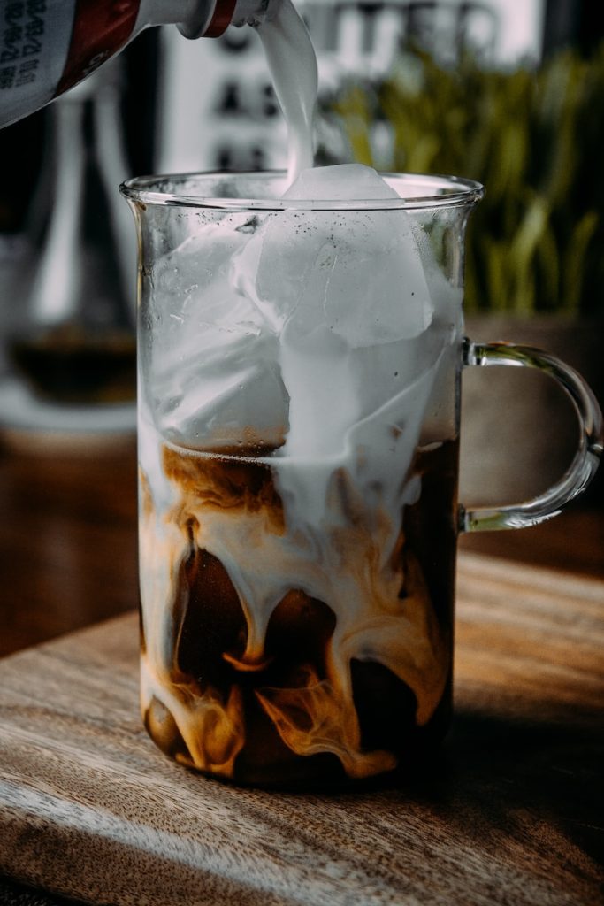 clear glass mug with ice cubes and brown liquid